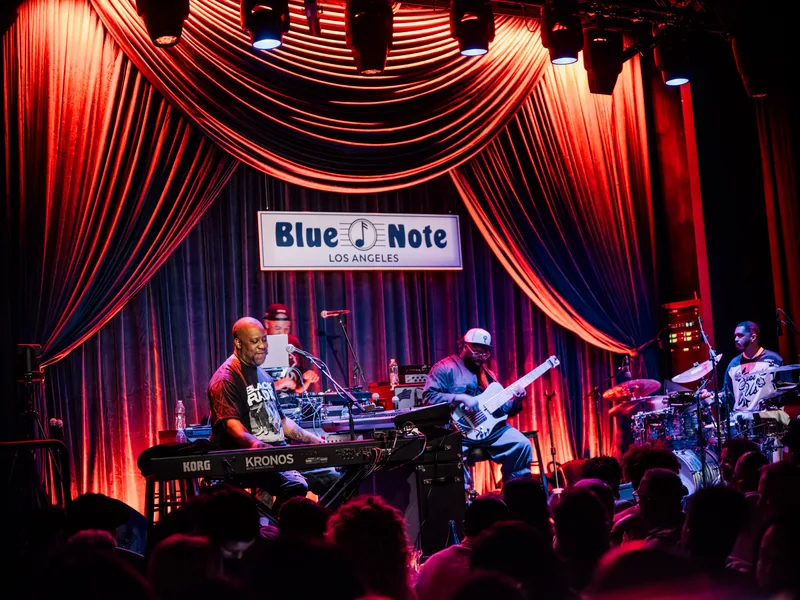 Robert Glasper and band performing beneath red and blue curtains at Blue Note Los Angeles