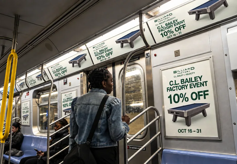 Paired C.L. Bailey Factory Event advertisements in a train interior mockup
