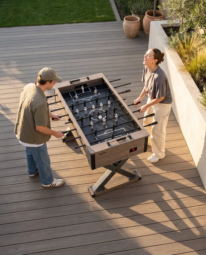 Two people playing foosball on a deck at golden hour